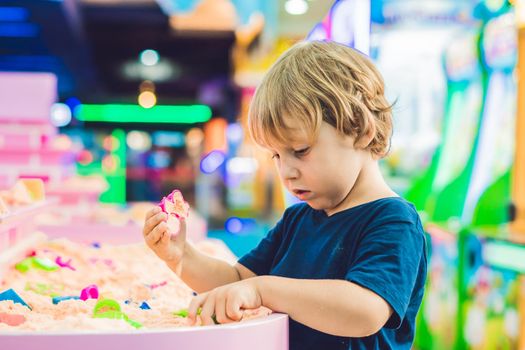 Boy playing with kinetic sand in preschool. The development of fine motor concept. Creativity Game concept.