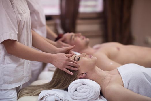 happy young beautiful couple enjoying head massage at the spa