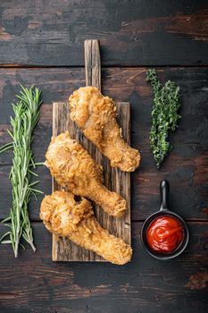 Crispy fried chicken cuts on dark wooden background, top view.