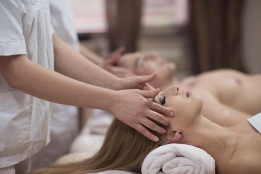 happy young beautiful couple enjoying head massage at the spa