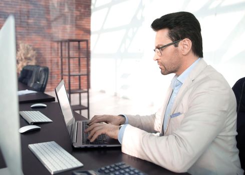 behind the glass.serious businessman typing on a laptop. business concept