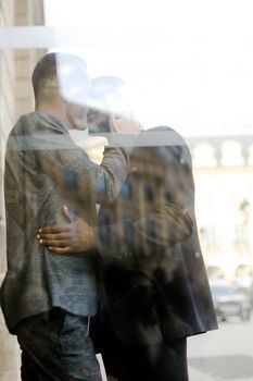 Reflection in window of two kissing boys, afro american and caucasian. Concept of gays and lgbt.