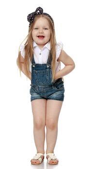 Cheerful, round-faced little girl with a bow on my head in short denim jumpsuit. Girl laughing looking at camera - Isolated on white background