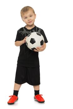 Portrait of a cheerful little boy football player in black uniform. The boy holds a hand soccer ball. Portrait in full growth - Isolated on white background