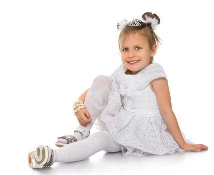 Smiling little Princess in a magnificent white dress. Girl sitting on the floor clasping his hand knee . Looking at the camera a happy look - Isolated on white background