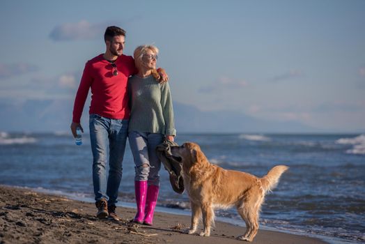 Couple Running On The Beach Holding Their Hands with dog On autmun day