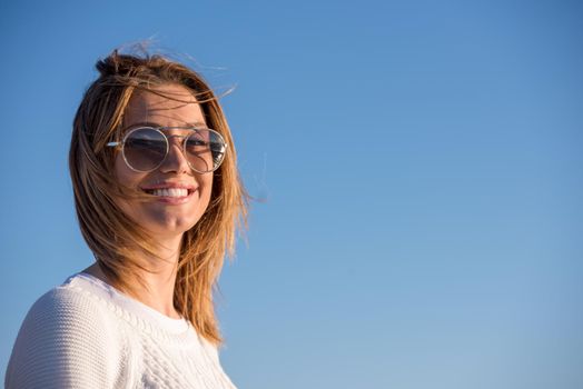 Young woman on the beach. The girl enjoying the warm autumn day. Portrait of beautiful girl near the water