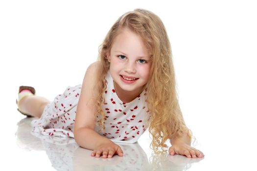 Beautiful little girl lies on the floor on a white background. The concept of a happy childhood, well-being in the family. Isolated.