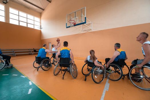 Disabled War or work veterans mixed race and age basketball teams in wheelchairs playing a training match in a sports gym hall. Handicapped people rehabilitation and inclusion concept.Hi quality photo