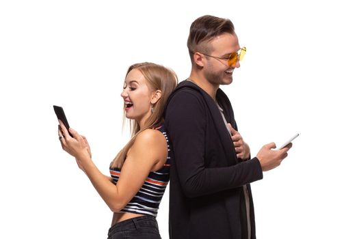 Man and woman stand with their backs to each other with telephones in their hands on white background. Studio shot