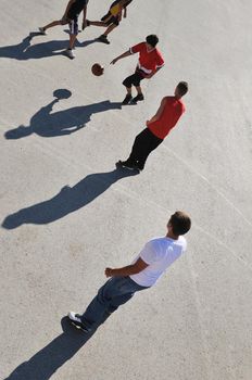 gorup of young boys who playing basketball outdoor on street with long shadows and bird view perspective