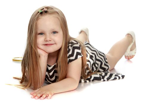 Happy little girl with long blond hair below the shoulders. Girl lying on the floor, leaning on the arm .She looks at the camera - Isolated on white background