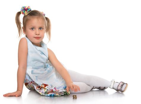 Cute little girl with a long ponytail down to his shoulders . Girl sitting on the floor . She puts a pile of coins - Isolated on white background