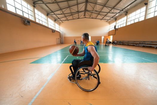 Disabled War or work veterans mixed race and age basketball teams in wheelchairs playing a training match in a sports gym hall. Handicapped people rehabilitation and inclusion concept. Top view.