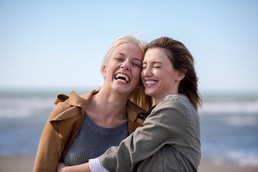 two cute young women smiling and enjoying life on an autumn walk along the ocean