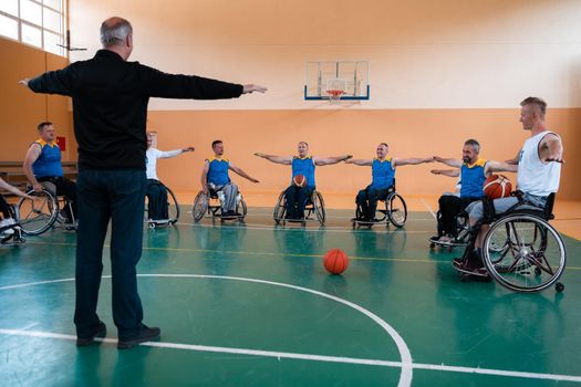 the selector of the basketball team with a disability stands in front of the players and shows them the stretching exercises before the start of training. Selective focus 
