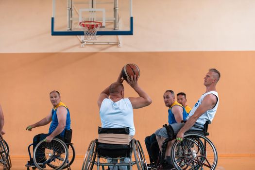 Disabled War or work veterans mixed race and age basketball teams in wheelchairs playing a training match in a sports gym hall. Handicapped people rehabilitation and inclusion concept.Hi quality photo