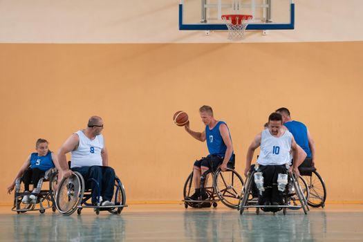 Disabled War veterans mixed race opposing basketball teams in wheelchairs photographed in action while playing an important match in a modern hall. High quality photo