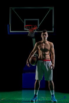 Basketball player portrait  on basketball court holding ball with black isolated background