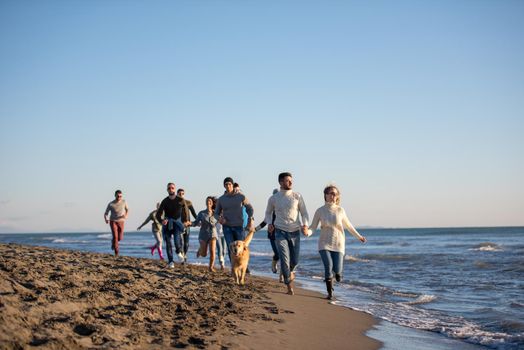 group of young friends spending day together running on the beach during autumn day