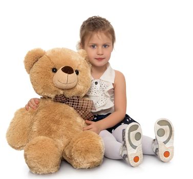 Cute little girl hugging a big Teddy bear . Girl sitting on the floor - Isolated on white background
