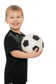 Portrait of a cheerful little boy football player in black uniform. The boy holds a hand soccer ball.Close-up - Isolated on white background