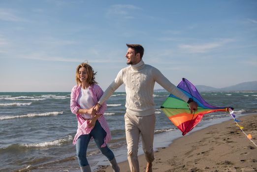 Young Couple having fun and Playing With A Kite On The Beach at autumn day