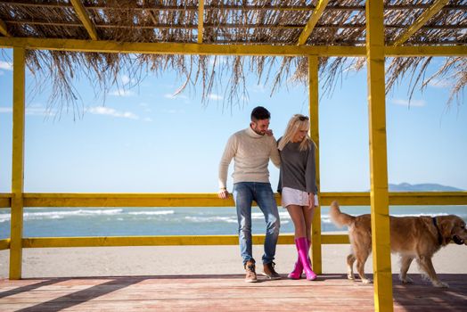 Couple With A Dog enjoying time  together On The Beach at autumn day