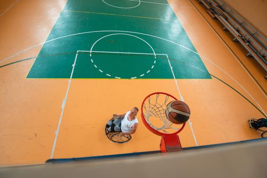 tow view photo of a war veteran playing basketball in a modern sports arena. The concept of sport for people with disabilities. High quality photo. Selective focus 