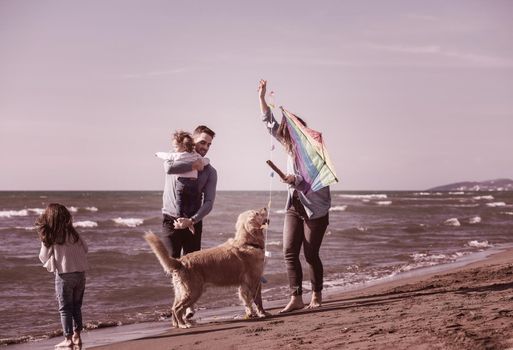 happy young family with kids having fun with a dog and  kite at beach during autumn day filter