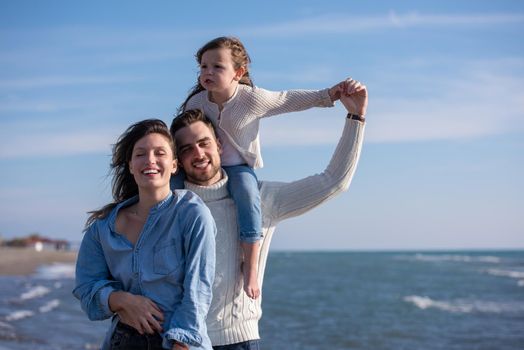 Family with kids resting and having fun at beach during autumn day