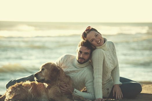 Couple With A Dog enjoying time  together On The Beach at autumn day