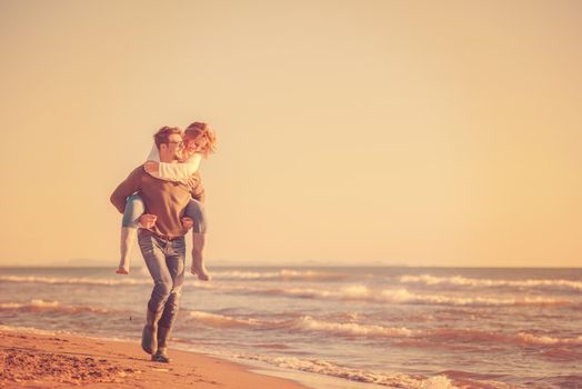 Men Giving Piggy Back Rides to his girlfriend At Sunset By The Sea, autumn time