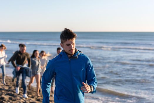 group of young friends spending day together running on the beach during autumn day