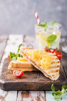 Hot fresh hawaii toast sandwich with ham, pineapple, tomato and cheese on wooden board. Healthy summer food concept with free space for text.