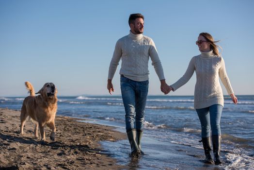 Couple Running On The Beach Holding Their Hands with dog On autmun day