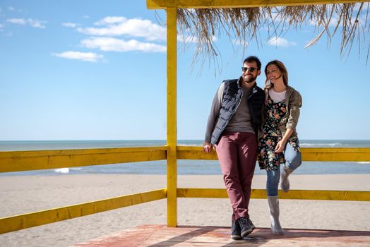 Happy couple enyojing time together on beach during autumn day