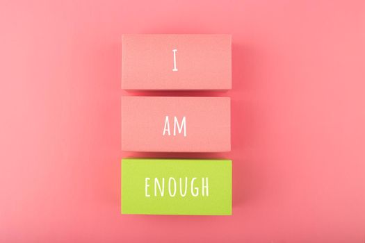 I am enough concept with words written on colorful rectangles against bright pink background. Mental health and self love concept