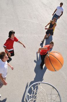 gorup of young boys who playing basketball outdoor on street with long shadows and bird view perspective