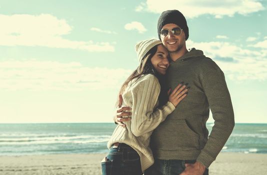 Happy couple enyojing time together on beach during autumn day