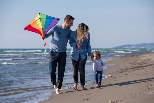 young family with kids resting and having fun with a kite at beach during autumn day