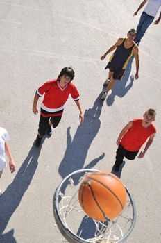 gorup of young boys who playing basketball outdoor on street with long shadows and bird view perspective