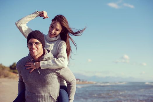 Men Giving Piggy Back Rides his girlfriend At Sunset By The Sea, autumn time