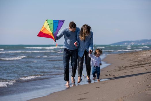 young family with kids resting and having fun with a kite at beach during autumn day