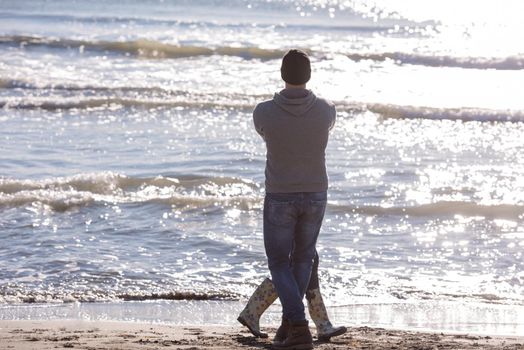 Young couple having fun walking and hugging on beach during autumn sunny day