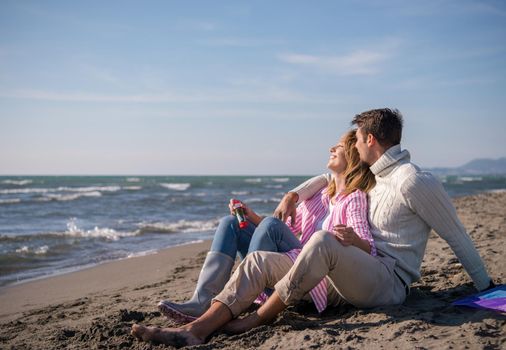 Young Couple having fun and making soap bubbles On The Beach at autumn day