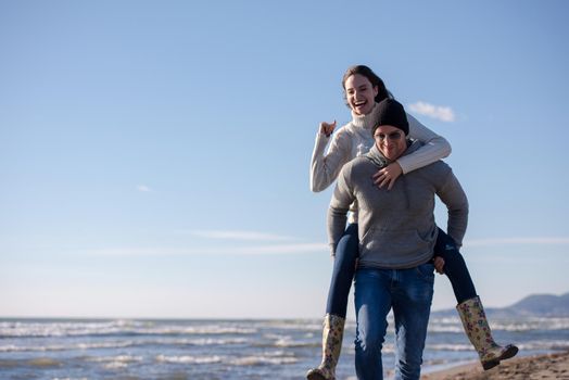 Men Giving Piggy Back Rides his girlfriend At Sunset By The Sea, autumn time