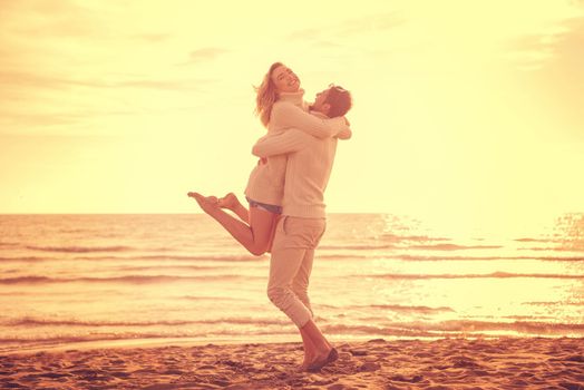 Young couple having fun walking and hugging on beach during autumn sunny day filter