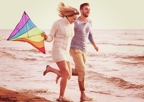 Young Couple having fun and Playing With A Kite On The Beach at autumn day filter