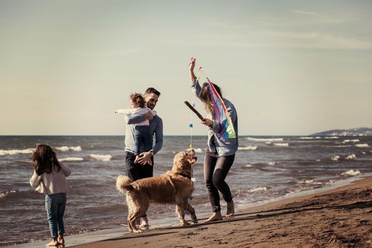 happy young family with kids having fun with a dog and  kite at beach during autumn day filter